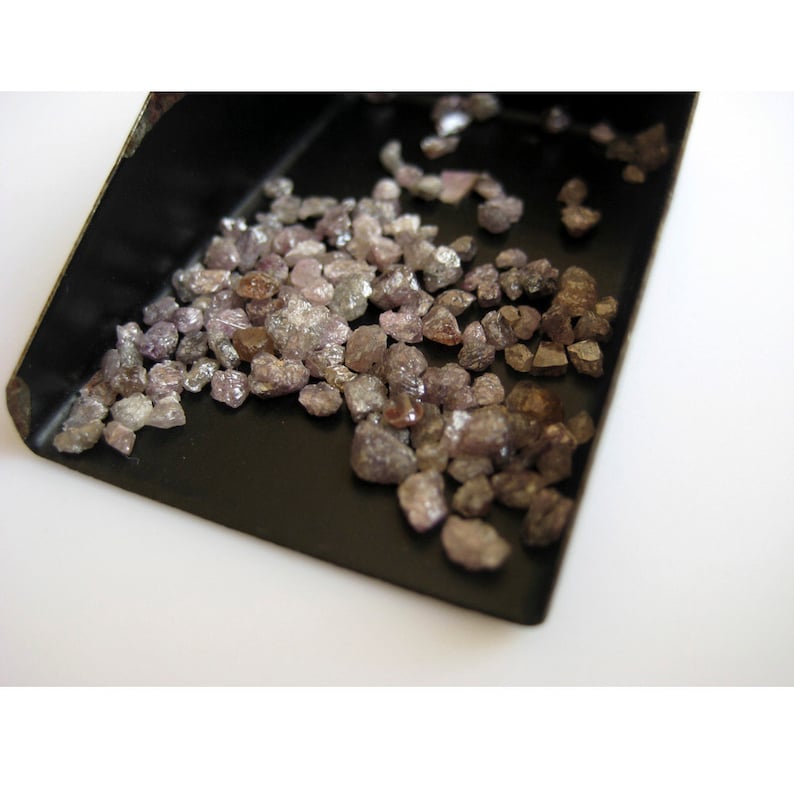 May include: A small black tray filled with a large quantity of rough, unpolished, pink and brown diamonds.