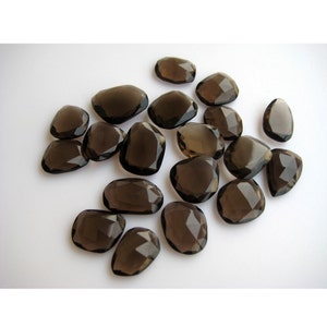 May include: A collection of 18 faceted smoky quartz gemstones in various sizes and shapes. The stones are a dark brown color and have a smooth, polished finish.