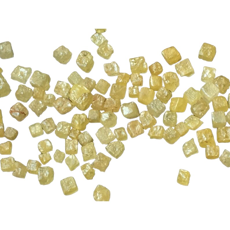 May include: A scattering of small, pale yellow, faceted diamonds on a white background.