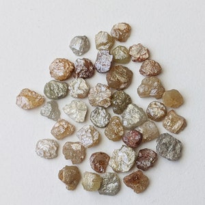 Peut inclure: Une collection de diamants bruts non taillés dans différentes nuances de brun, gris et blanc. Les diamants sont de forme irrégulière et ont une apparence naturelle non polie.