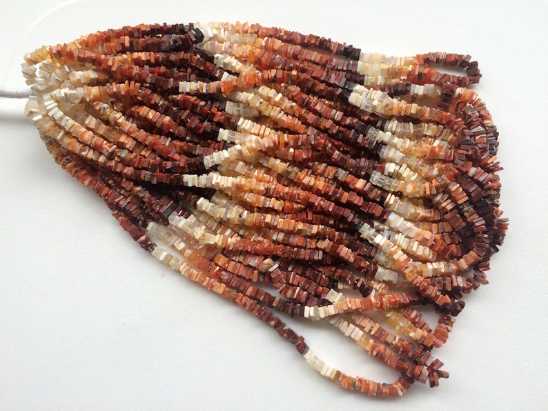 May include: A strand of multi-colored gemstone beads. The beads are square shaped and have a mix of red, orange, and white colors.