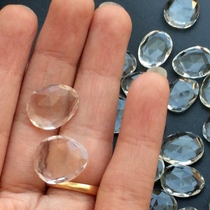 Peut inclure: Une main tenant deux pointes de cristal de quartz transparent, avec un tas de cristaux similaires en arri&egrave;re-plan.