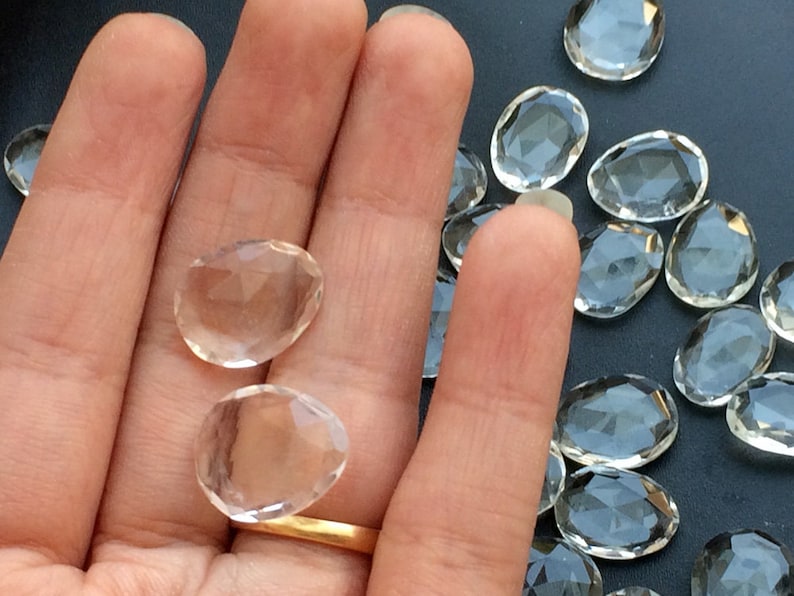 Peut inclure: Une main tenant deux pointes de cristal de quartz transparent, avec un tas de cristaux similaires en arri&egrave;re-plan.