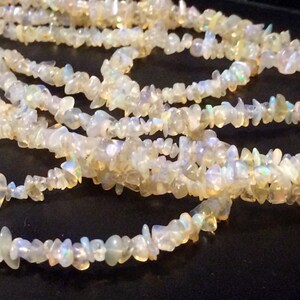 May include: A strand of white opal chip beads. The beads are irregular in shape and have a slight iridescent sheen.