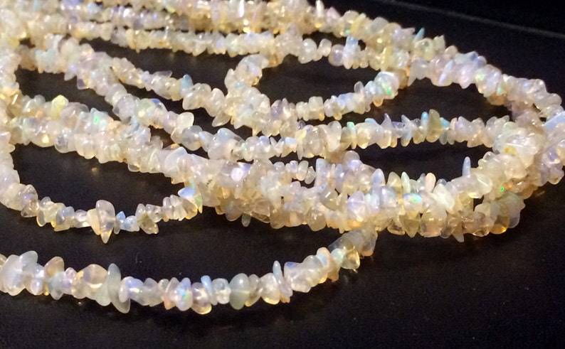 May include: A strand of white opal chip beads. The beads are irregular in shape and have a slight iridescent sheen.