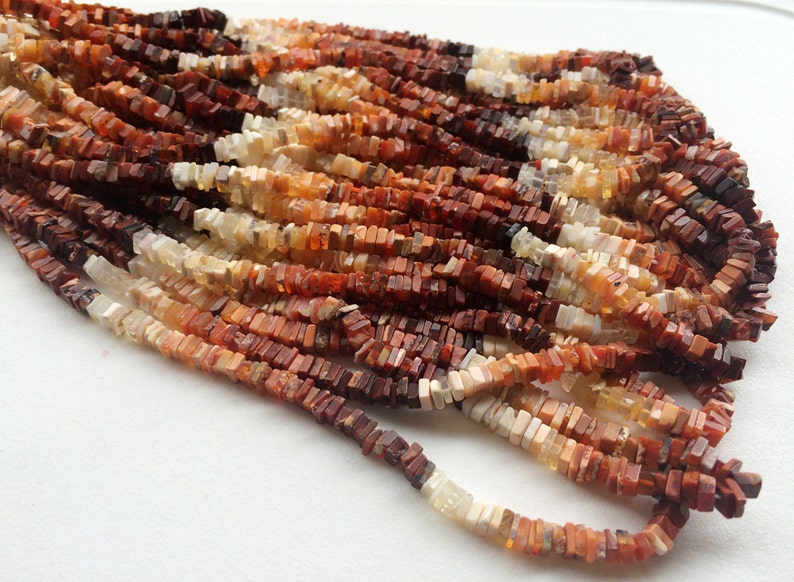 May include: A strand of multi-colored, square-shaped opal beads. The beads are a mix of white, orange, and brown.