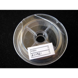 May include: A clear plastic spool of silver wire with a white label that reads "( ) 0.21mm ( ) 100m".