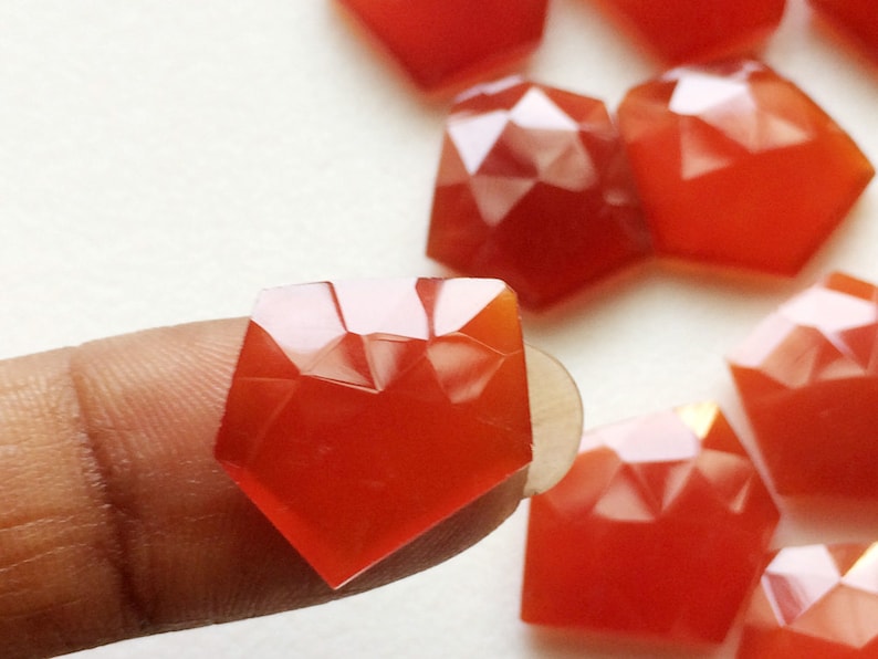 Puede incluir: Una colecci&oacute;n de piedras preciosas de cornalina facetadas en una variedad de tama&ntilde;os y formas. Las piedras preciosas son de color naranja intenso y tienen un acabado brillante.
