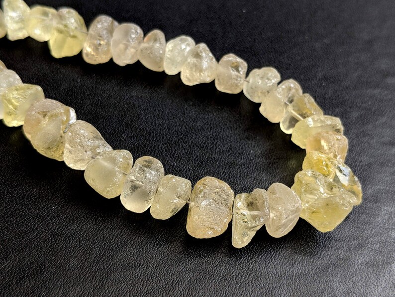 May include: A strand of yellow citrine gemstone beads, each bead is irregularly shaped and has a translucent appearance.