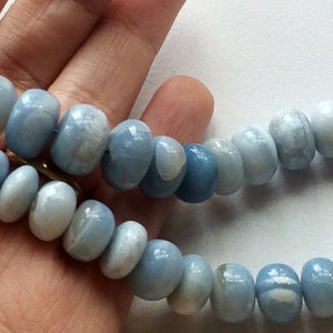 May include: A strand of light blue gemstone beads with a white marbled pattern. The beads are round and smooth, and they are strung on a clear thread.