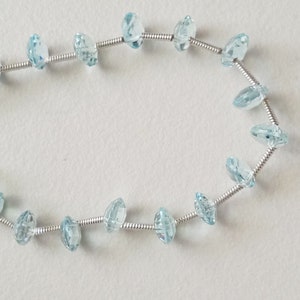 May include: A strand of light blue gemstone beads strung on a silver wire.