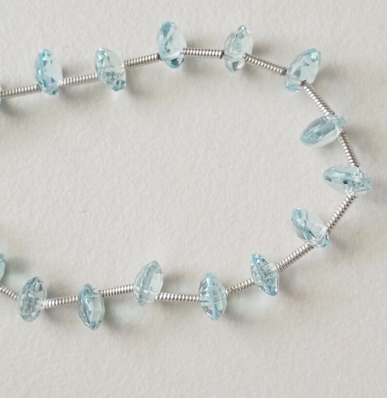 May include: A strand of light blue gemstone beads strung on a silver wire.