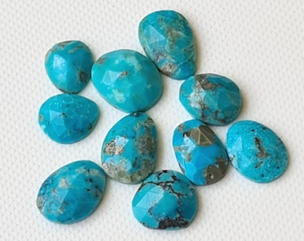 Puede incluir: Diez cabujones de turquesa, cada uno con un patrón único de vetas marrones y negras, están dispuestos sobre una superficie blanca. Las piedras tienen forma ovalada y un acabado liso y pulido.