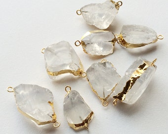 May include: Eight clear quartz crystal pendants with gold-plated jump rings. The crystals are irregular in shape and have a natural, raw look.