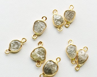 May include: Eight gold-toned connector charms with raw, clear, faceted, diamond-shaped stones. The charms have two loops on each side for attaching to jewelry.