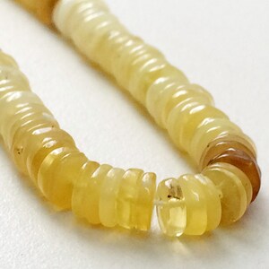 May include: A strand of yellow opal beads, each bead is a stack of thin, round, translucent discs.