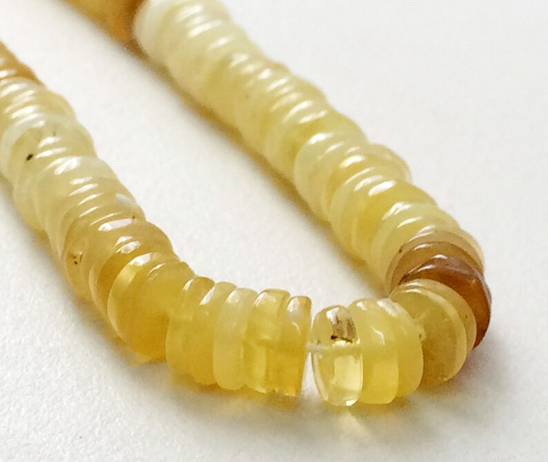May include: A strand of yellow opal beads, each bead is a stack of thin, round, translucent discs.