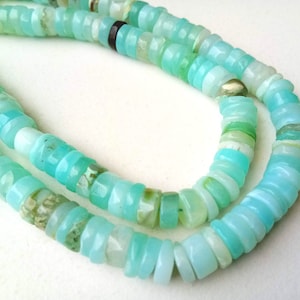 May include: A strand of light blue opal beads, with a mix of light and dark blue tones, arranged in a double row.