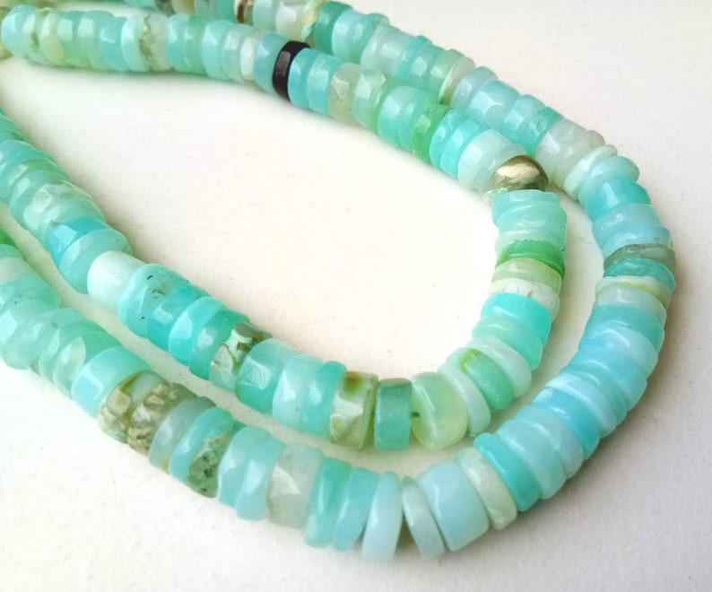 May include: A strand of light blue opal beads, with a mix of light and dark blue tones, arranged in a double row.