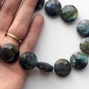 May include: A strand of faceted labradorite gemstone beads in shades of green, blue, and gray. The beads are round and have a smooth, polished finish.
