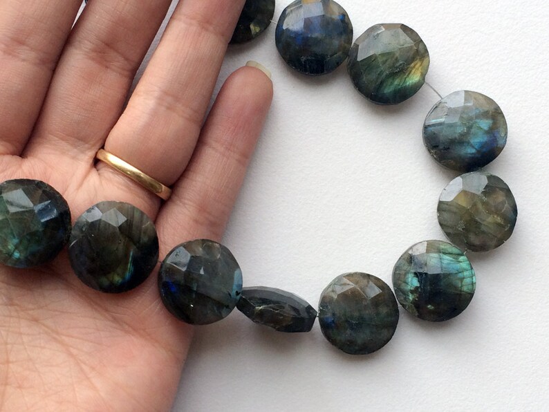 May include: A strand of faceted labradorite gemstone beads in shades of green, blue, and gray. The beads are round and have a smooth, polished finish.