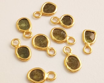 May include: Ten gold-toned metal charms with a teardrop-shaped green gemstone. Each charm has a small loop for attaching to jewelry.