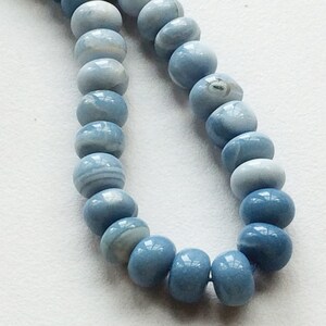 May include: A strand of light blue gemstone beads. The beads are round and have a smooth, polished finish.