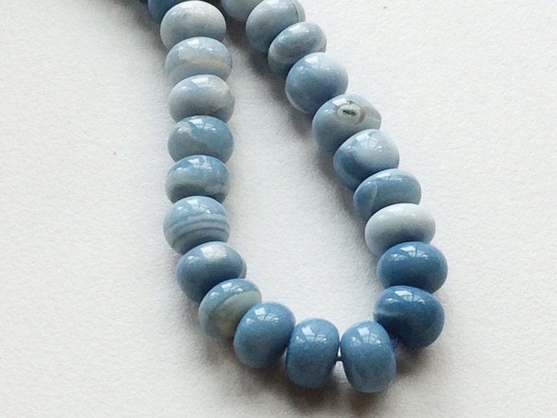 May include: A strand of light blue gemstone beads. The beads are round and have a smooth, polished finish.