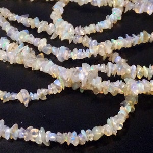 May include: A strand of white opal chip beads. The beads are irregular in shape and have a slight iridescent sheen.