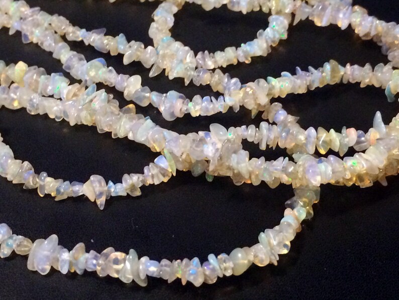 May include: A strand of white opal chip beads. The beads are irregular in shape and have a slight iridescent sheen.