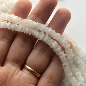 Puede incluir: Una hebra de cuentas de piedra lunar blanca, cada cuenta tiene forma de chip rectangular.