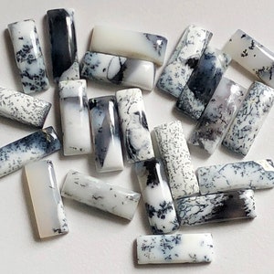 May include: A collection of 17 white and black dendritic opal cabochons. The cabochons are rectangular in shape and have a variety of patterns and sizes.