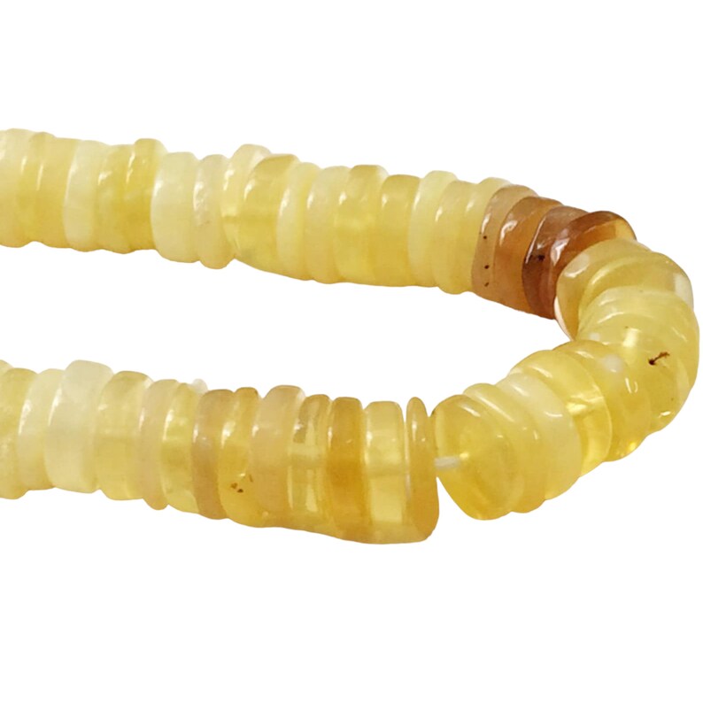 May include: A strand of yellow opal beads, each bead is a stack of thin, flat, rounded pieces of opal. The beads are strung on a clear thread.