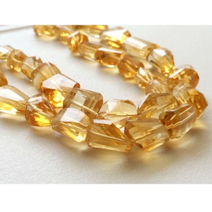 May include: A strand of faceted citrine beads in a golden yellow color. The beads are faceted and have a slightly irregular shape.