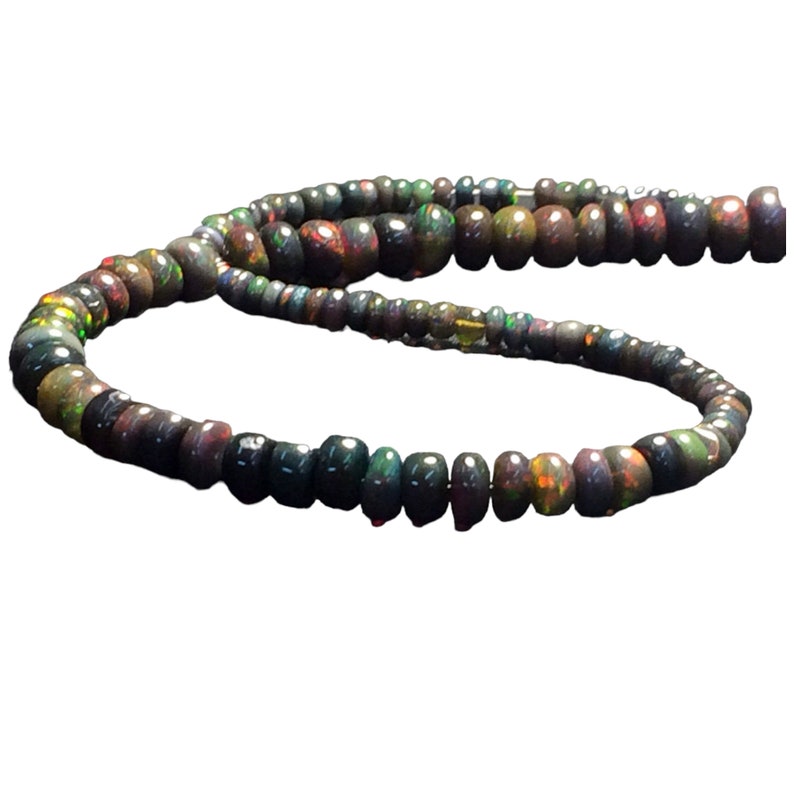 May include: A strand of black opal beads with iridescent colors. The beads are round and have a smooth, polished finish.
