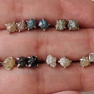 May include: A set of ten raw diamond earrings in various colors, including clear, brown, and gray. The earrings are set in silver.