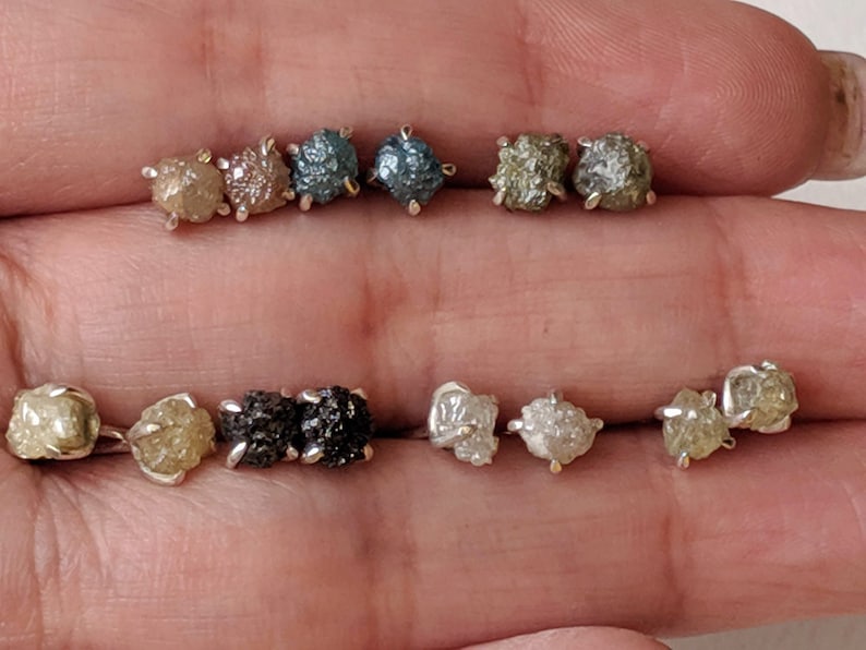May include: A set of ten raw diamond earrings in various colors, including clear, brown, and gray. The earrings are set in silver.