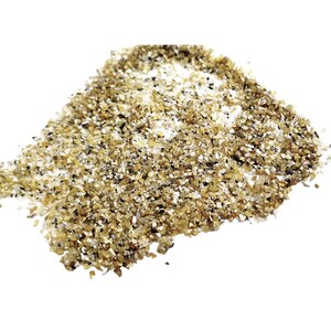 May include: A pile of small, golden, iridescent glass chips. The chips are irregular in shape and size, and they have a sparkly, glittery appearance.