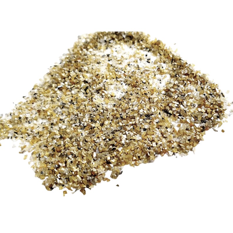 May include: A pile of small, golden, iridescent glass chips. The chips are irregular in shape and size, and they have a sparkly, glittery appearance.