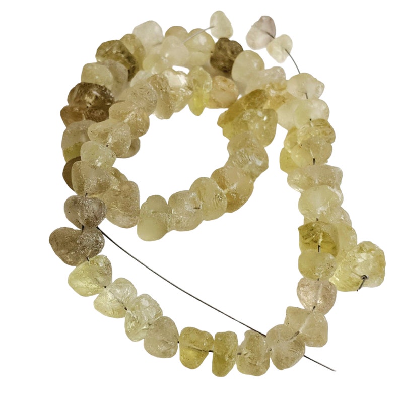 May include: A strand of light yellow and clear faceted gemstone beads. The beads are irregular in shape and have a rough, natural look. The beads are strung on a thin wire.