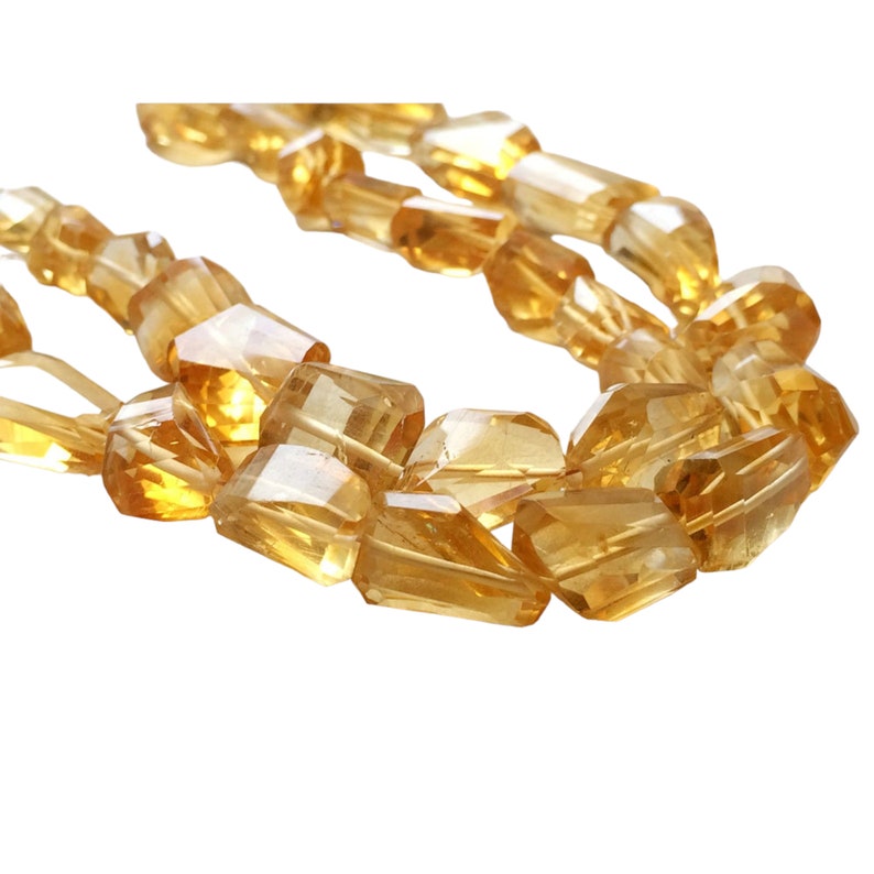 May include: A strand of faceted, golden citrine beads. The beads are cut in a rectangular shape with pointed edges. The beads are strung on a clear thread.