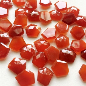 Puede incluir: Una colecci&oacute;n de 30 piedras de cornalina facetadas, cada una con una forma irregular &uacute;nica. Las piedras son de color rojo anaranjado intenso y tienen un acabado brillante.