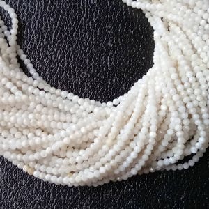 May include: A strand of white moonstone beads, each bead is faceted and has a slightly iridescent sheen.