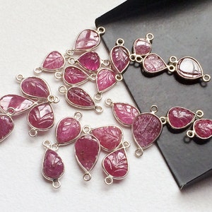 May include: A collection of pink ruby gemstone pendants with carved leaf designs. Each pendant has two silver jump rings for attaching to jewellery.
