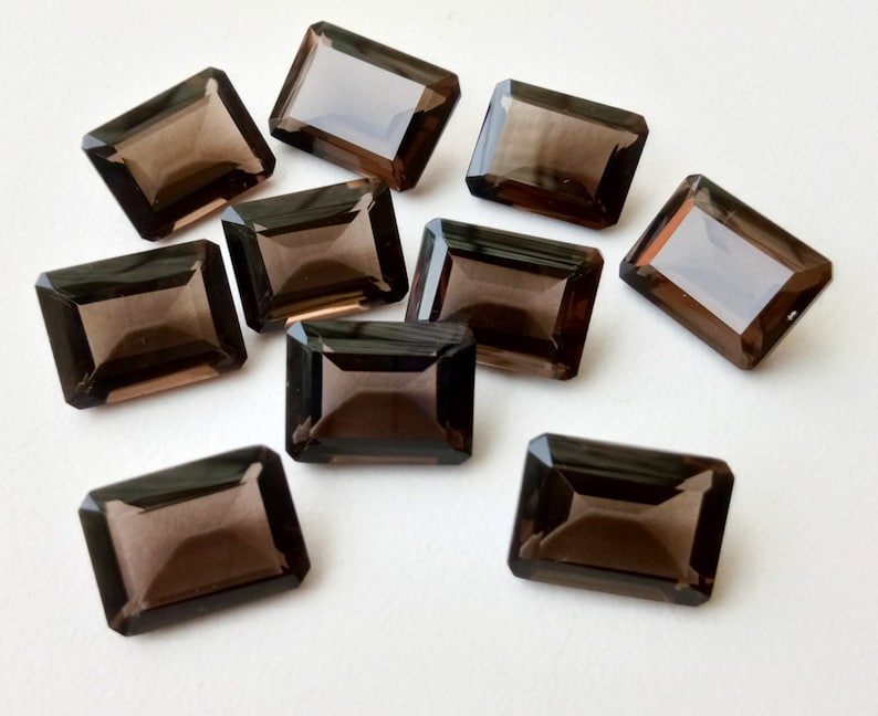 以下が含まれることがあります： 長方形のエメラルドカットの煙水晶の宝石が10個。宝石は濃い茶色で、滑らかで磨かれた仕上げになっています。