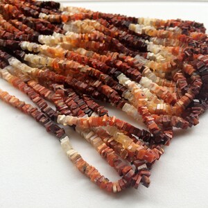May include: A strand of orange, red, and white gemstone beads. The beads are square and have a rough, natural texture.