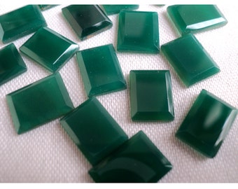 May include: A collection of loose, rectangular green gemstones with a smooth, polished surface and beveled edges. Each stone features a deep forest green hue and a flat top, arranged in a scattered pattern to showcase their uniform shape and finish.