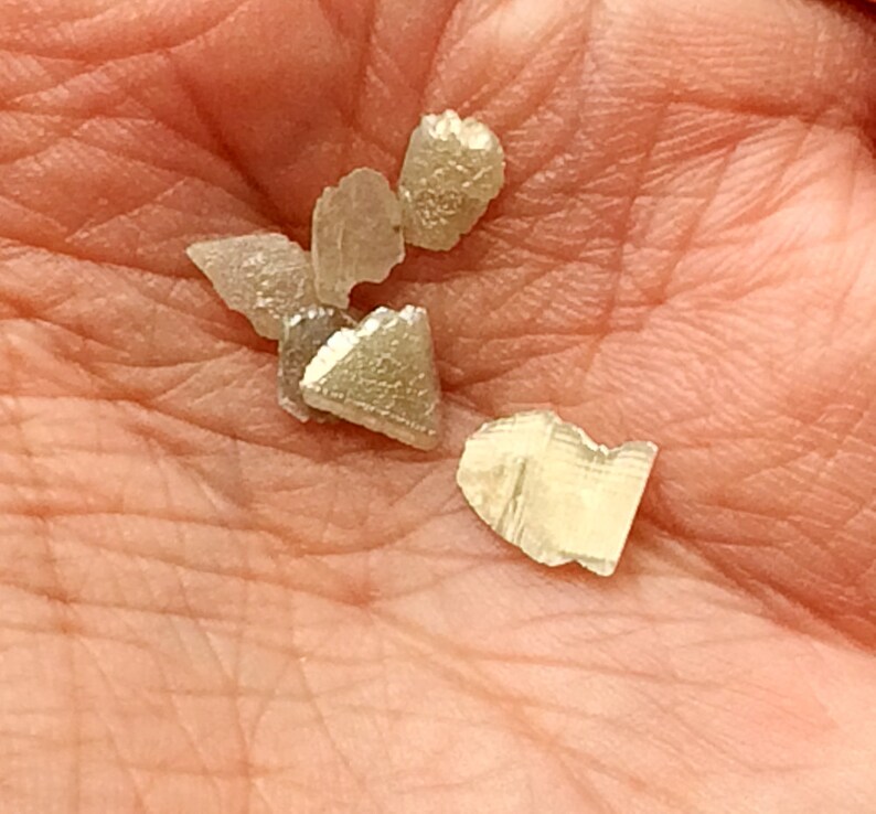 May include: A collection of small, clear, and translucent crystals with a slightly iridescent sheen. The crystals are irregularly shaped and have a variety of sizes.