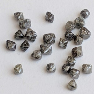 Puede incluir: Una colecci&oacute;n de peque&ntilde;os diamantes negros en bruto. Los diamantes son de diferentes formas y tama&ntilde;os, pero todos est&aacute;n cortados en forma cuadrada.