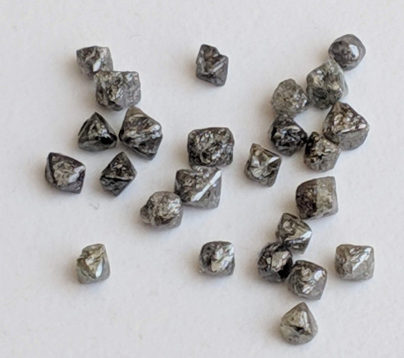 Puede incluir: Una colecci&oacute;n de peque&ntilde;os diamantes negros en bruto. Los diamantes son de diferentes formas y tama&ntilde;os, pero todos est&aacute;n cortados en forma cuadrada.